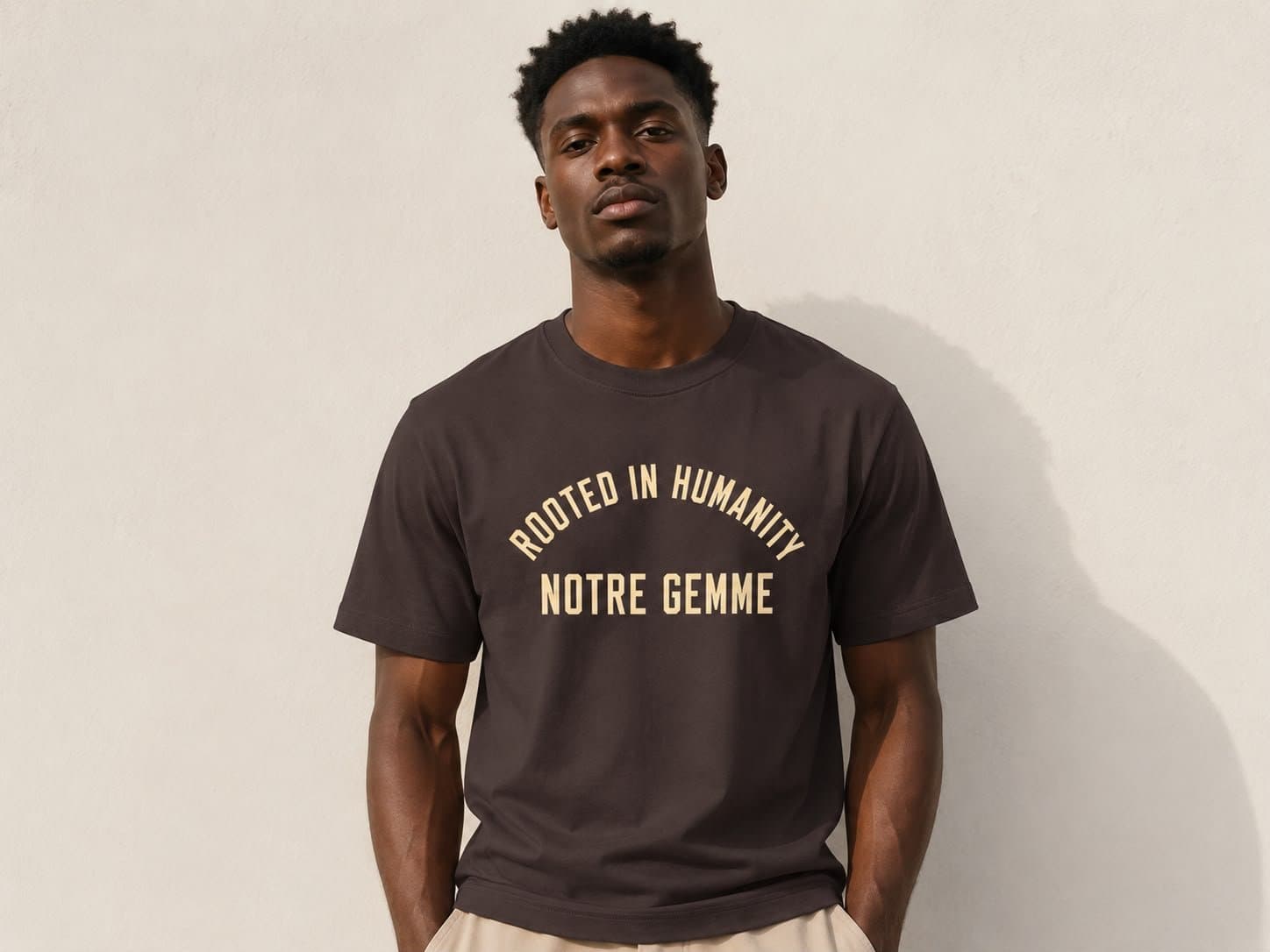 Notre Gemme Rooted in Humanity tee in brown — front, arched ROOTED IN HUMANITY / NOTRE GEMME print